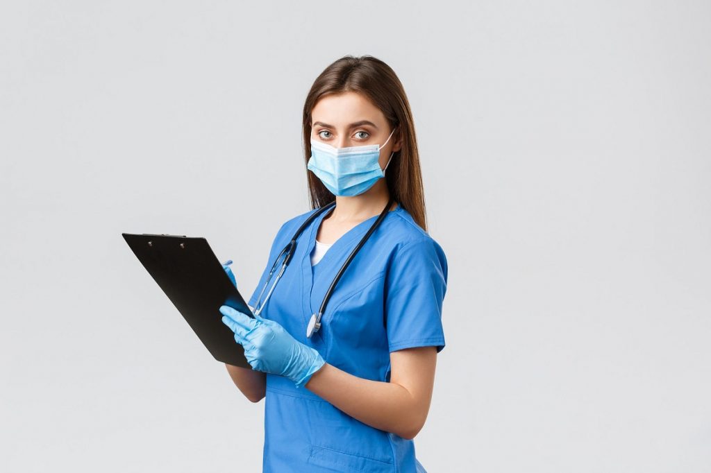 a nurse wearing a mask holding a file and pen 