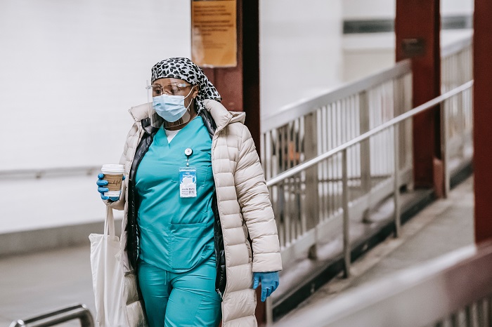 Black female nurse in uniform and protective mask on city street