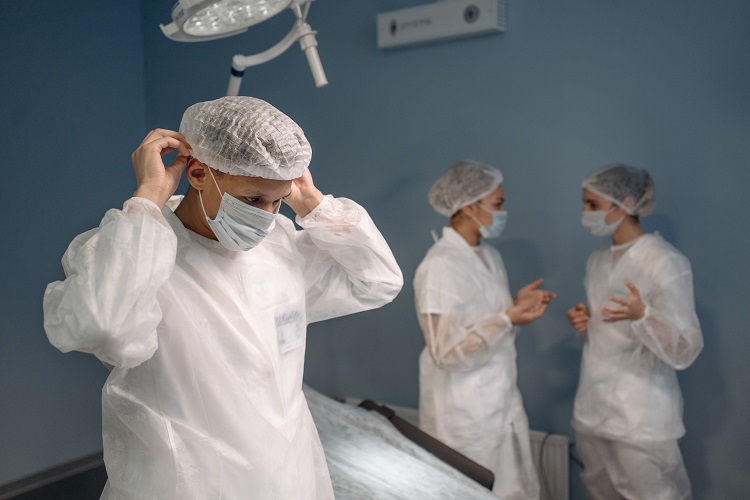 Doctors in Protective Suit Putting on a Face Mask Beside Two Other Doctor
