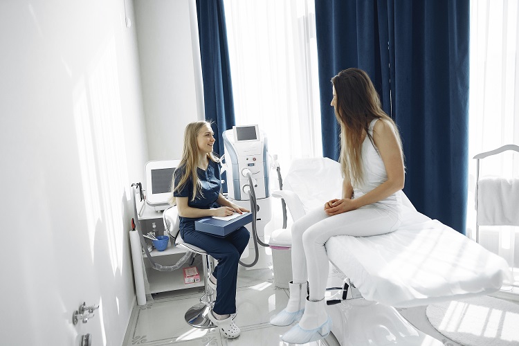 Nurse in Blue Scrub Suit Helping Patient Woman Sitting on Bed